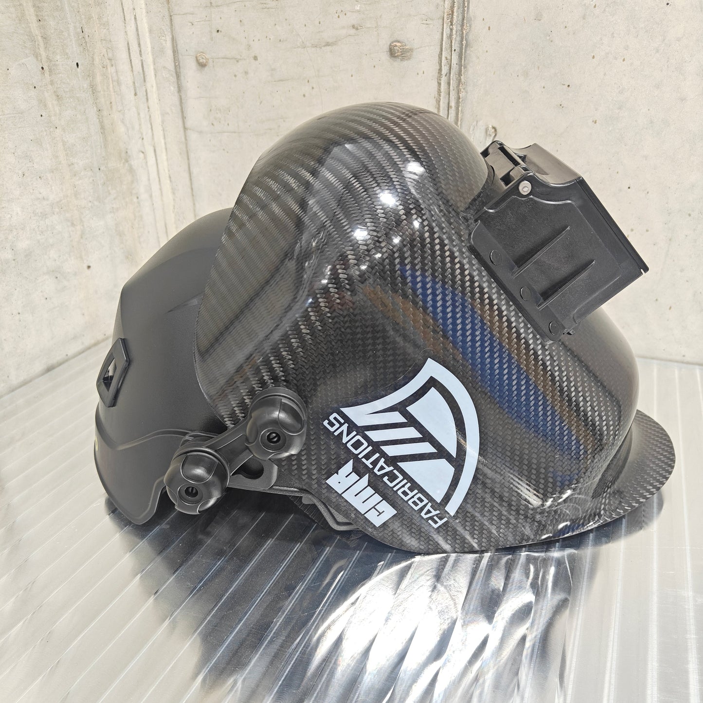 Carbon fiber helmet with a visible brand logo on a reflective surface.