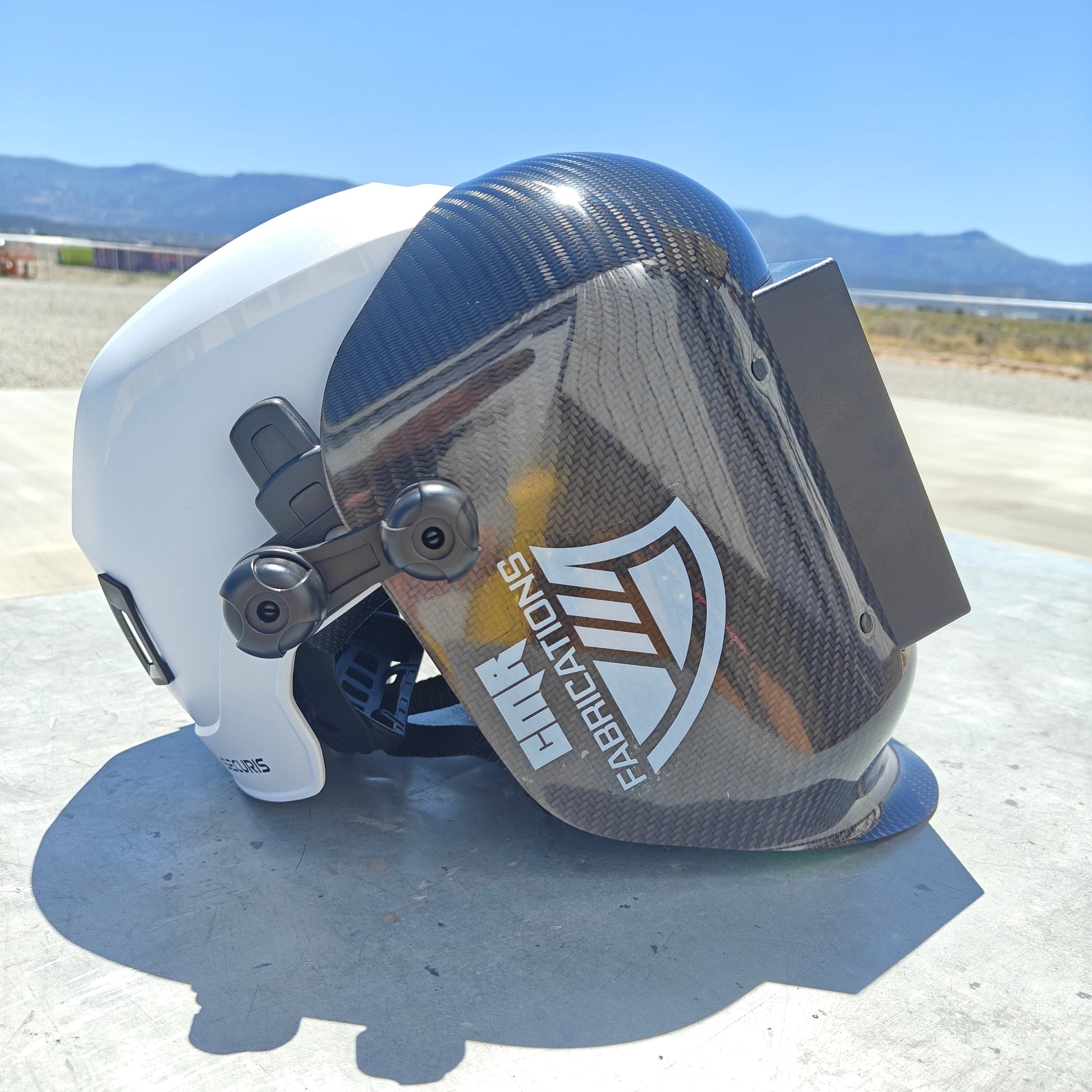 Helmet with visor and branding on a flat surface with a clear sky background