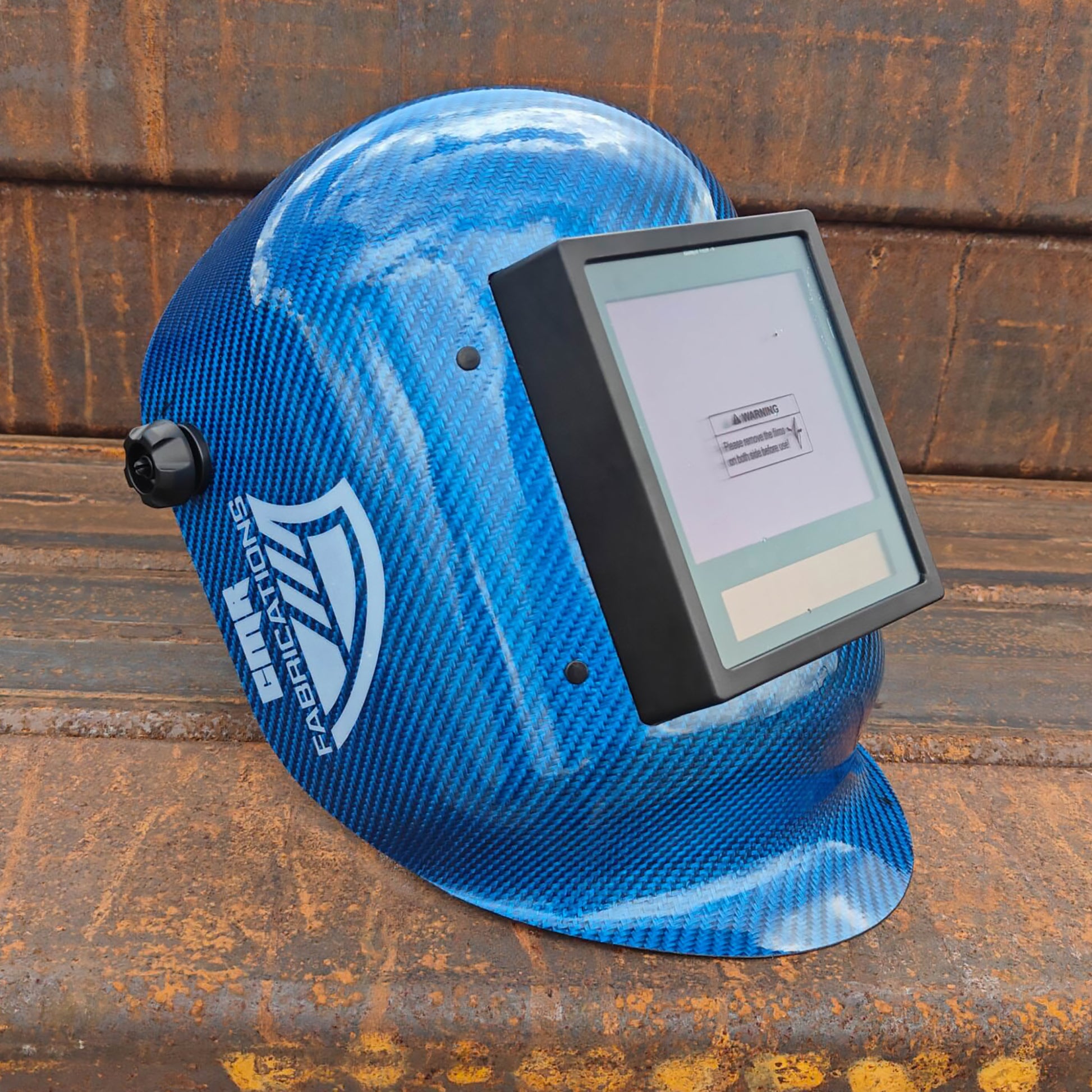 CMR Fabrications Carbon fiber Pipeliners Sugar scoop welding helmet Blue with digital display on a rusty metal surface