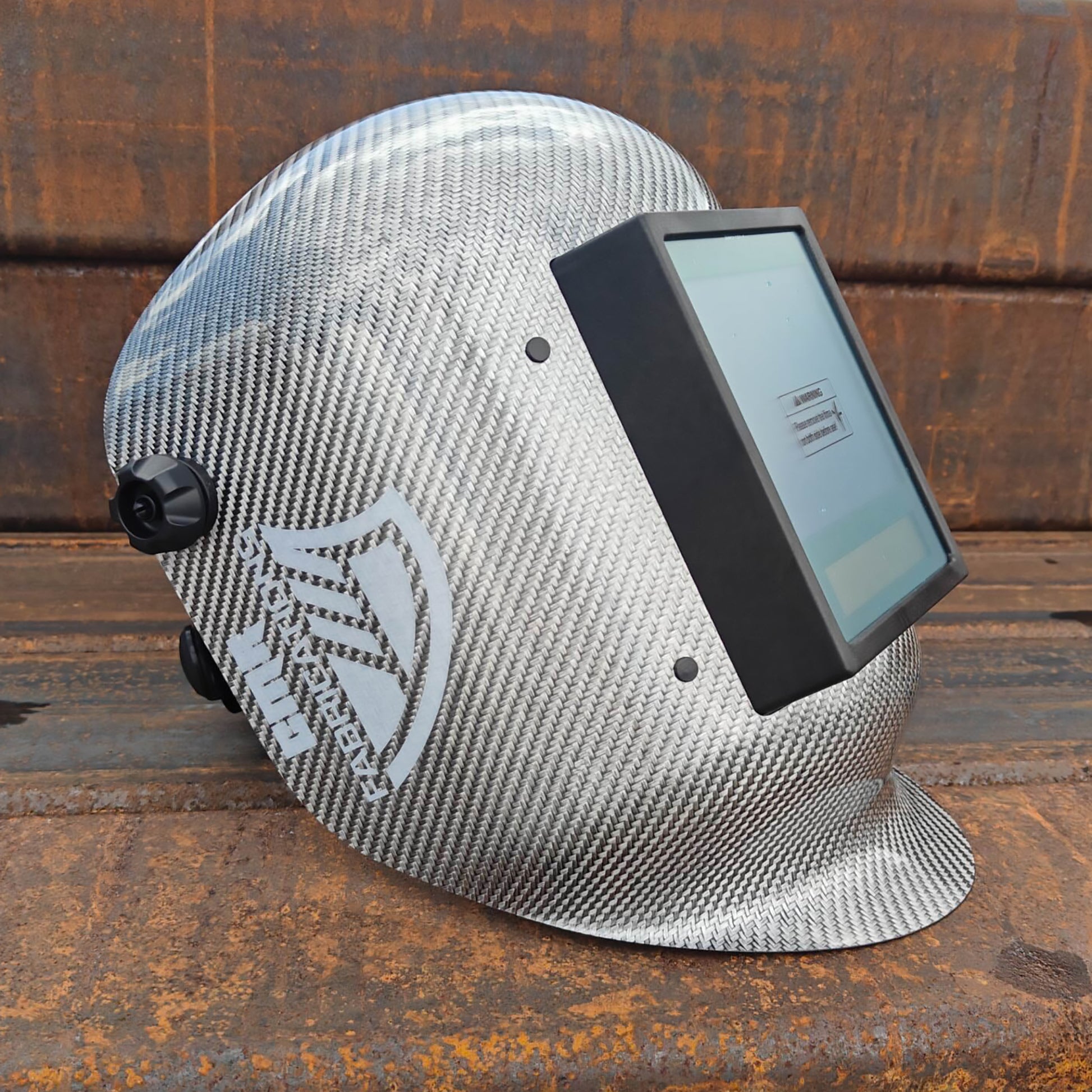 CMR Fabrications Carbon fiber Pipeliners Sugar scoop welding helmet titanium with digital display on a rust surface.
